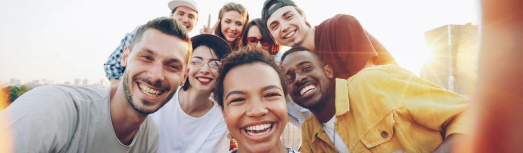 A diverse group of friends taking a joyful selfie outdoors during sunset.